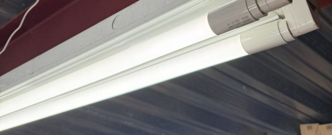 Two-tube strip light fixture mounted to a steel beam under a metal deck ceiling during an electrical job in Clarksville, MD